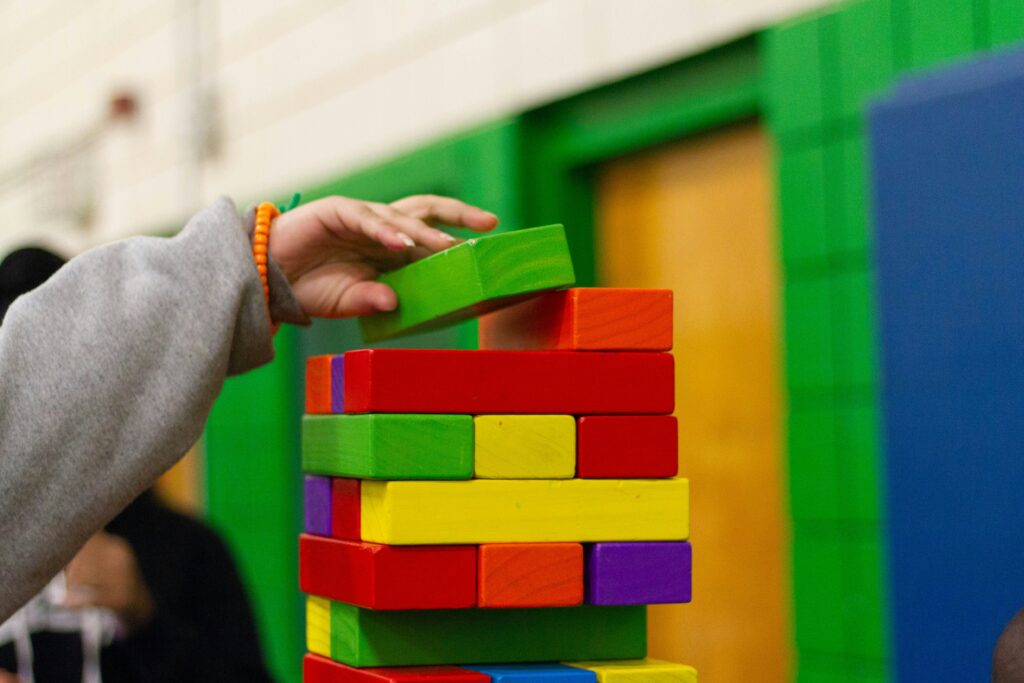 Eine Kinderhand setzte einen Bauklotz auf einen Turm