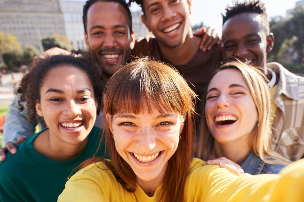 Eine Gruppe junger Erwachsender lacht in die Kamer und macht ein Selfie