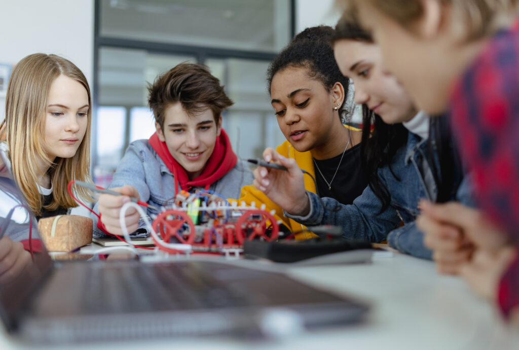 Eine Gruppe junger Schüler*innen baut und programmiert im Robotik-Unterricht elektrische Spielzeuge und Roboter.