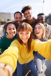 Eine Gruppe junger Erwachsener macht ein Selfie. Dabei schauen alle fröhlich in die Kamera.
