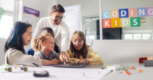 Ein männlicher Lehrer leitet Grundschüler in einem Codingkurs an.