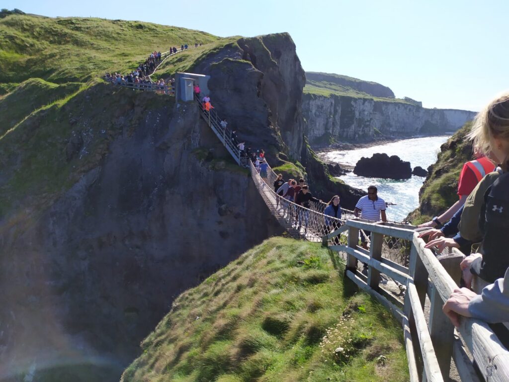 Menschen überqueren eine Hängebrücke zwischen zwei Bergfelsen