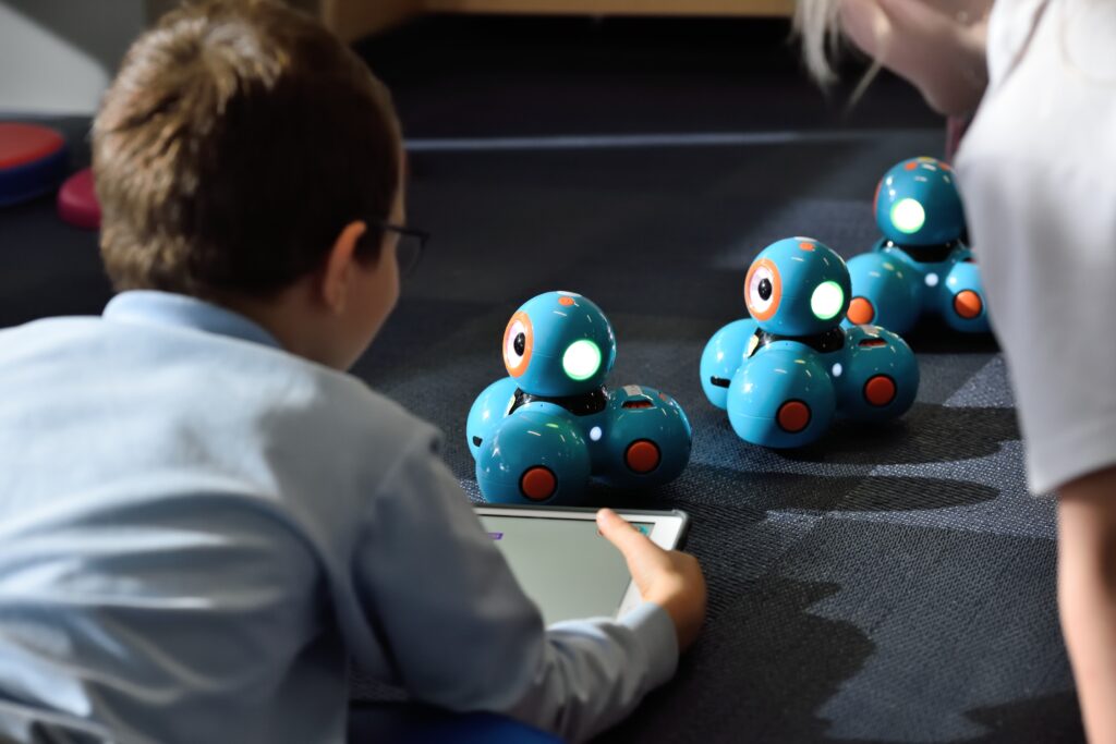 Zwei Kinder bringen kleine Roboter mit einem Tablet zum Fahren.