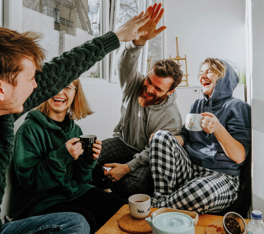 Gruppe junger Erwachsener, die gemeinsam Kaffee trinkt und sich ein High Five gibt
