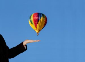 Ein bunter Heißluftballon ist vor einem komplett blauen Hintergrund zu sehen.