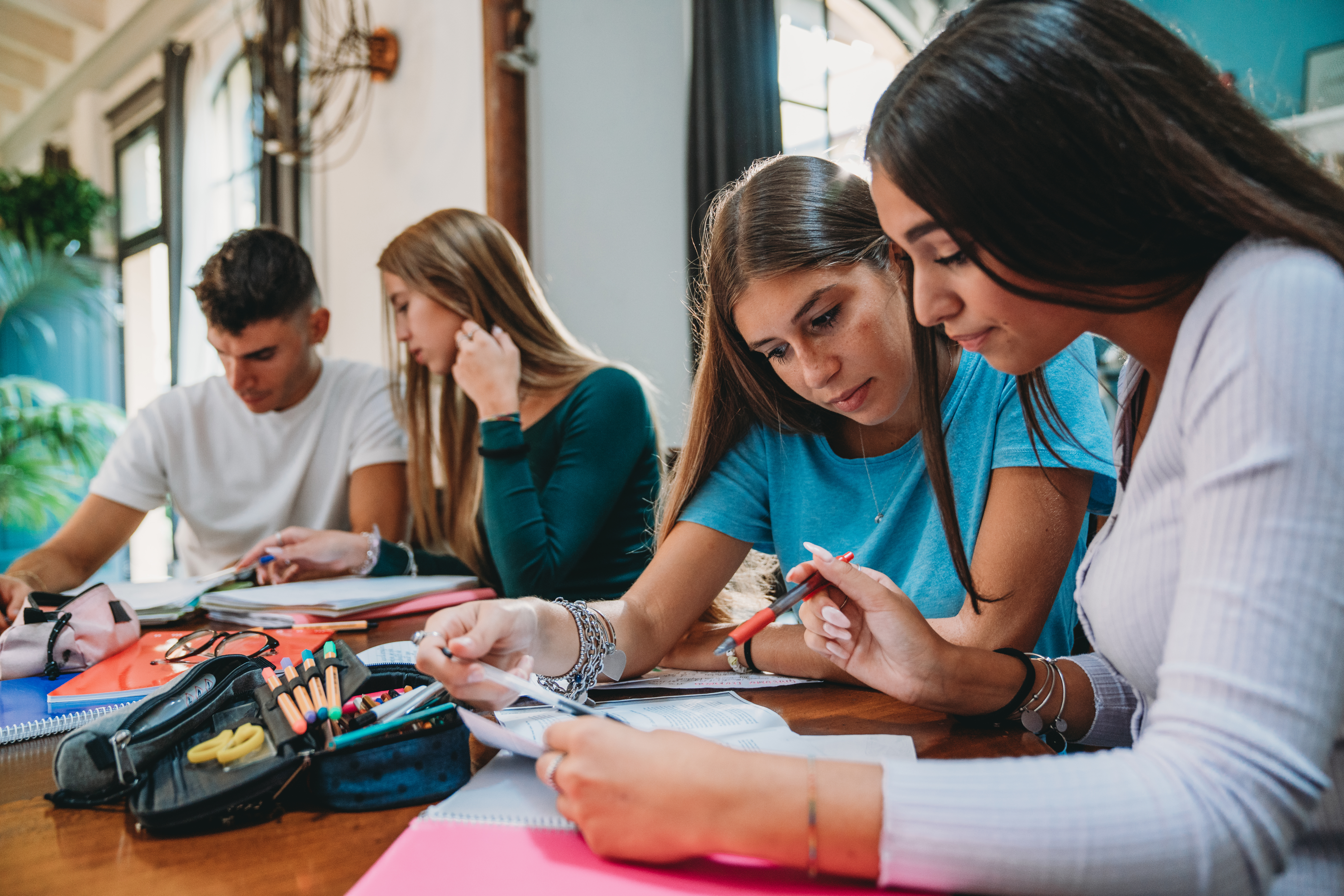 Vier Jugendliche sitzen an einem Tisch und lernen konzentriert.