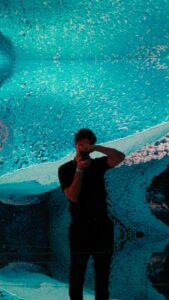 Ein junger Mann steht vor einer digital animierten Leinwand und fotografiert etwas.